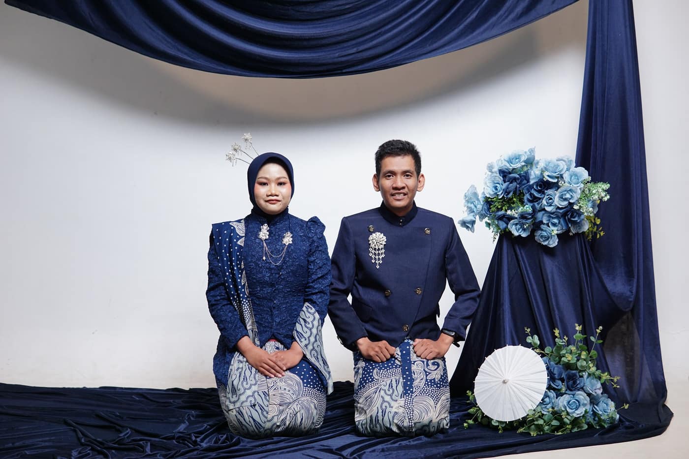 Ula dan Fadli duduk berdampingan di antara dekorasi biru
