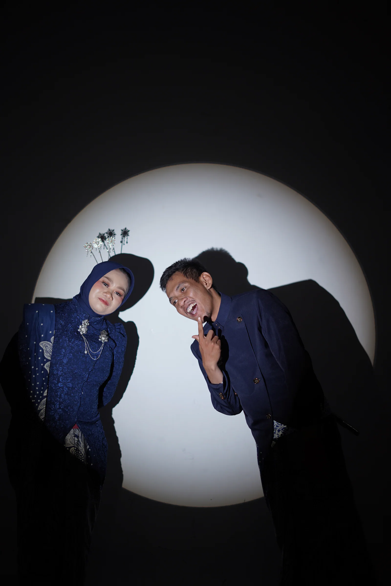 Dewi dan Fadli membungkuk ke kamera dengan ekspresi jenaka