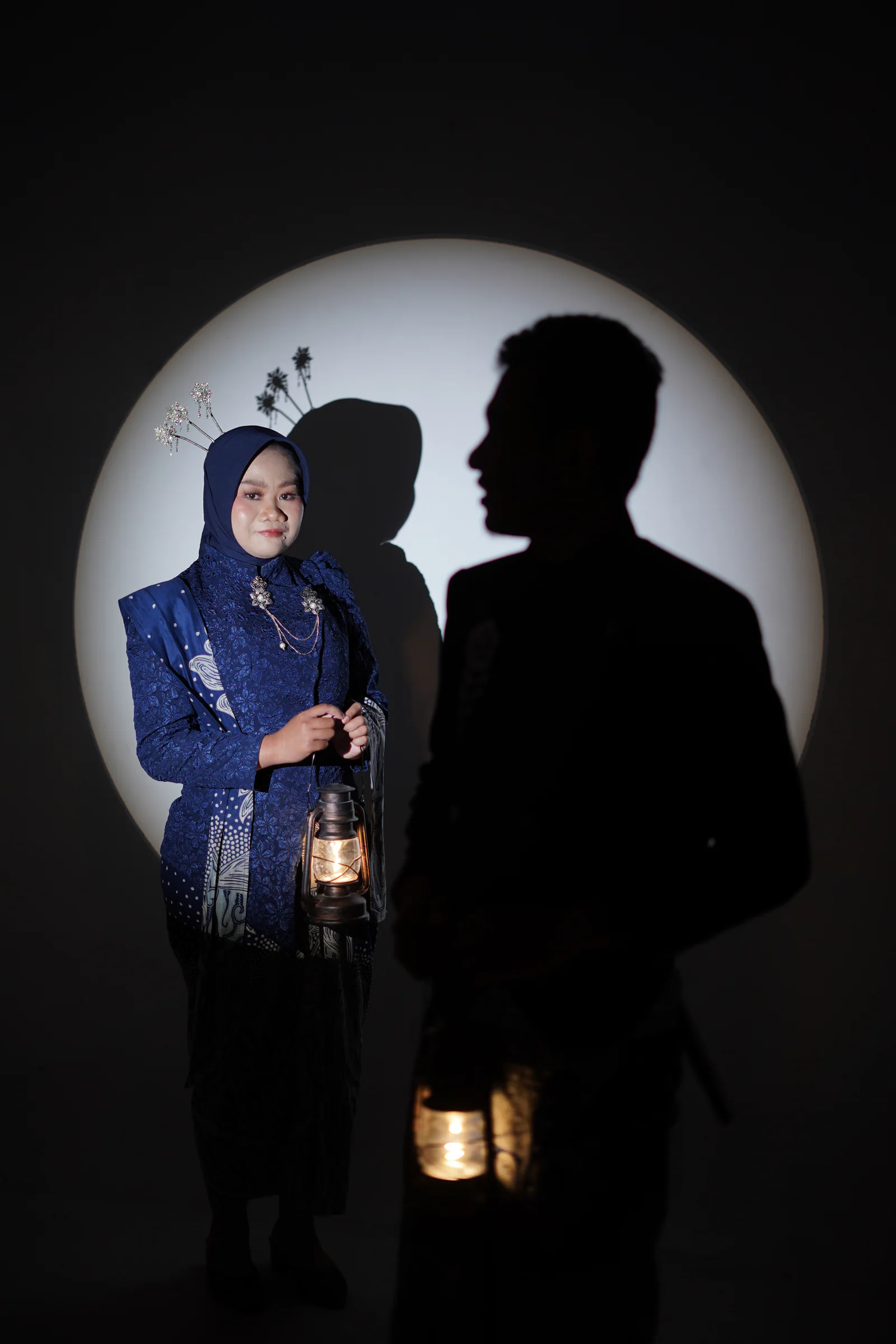 Dewi membawa lentera dengan siluet Fadli di dalam lingkar cahaya